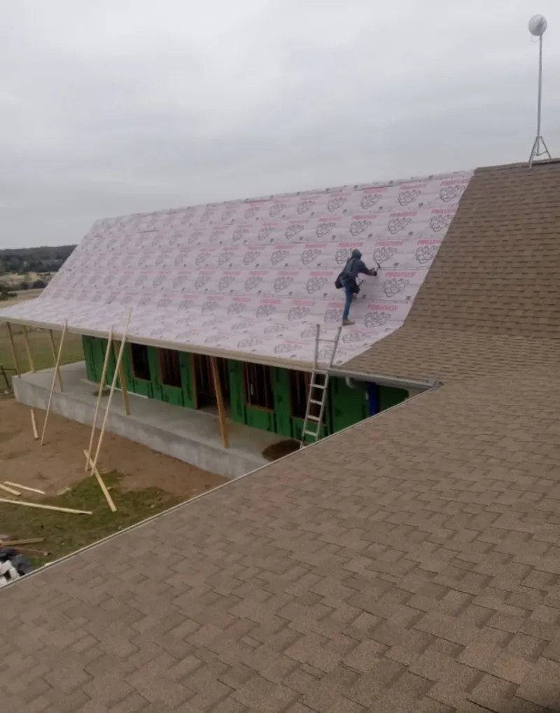 Worker preparing underlayment for a metal roof installation in Happy Valley